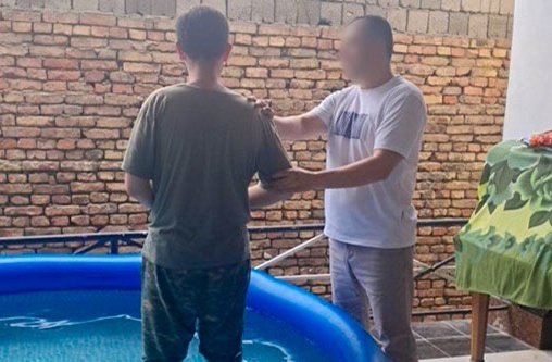 Ein Mann wird von einem anderen Mann in einem Pool getauft.
