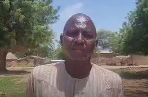 Ein afrikanischer Mann steht vor einem Dorf